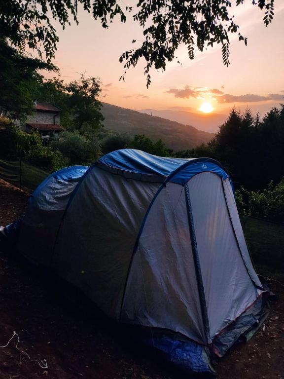 a tent on the ground with the sunset in the background at Agricampeggio Boschetto Gioioso in Barbiano