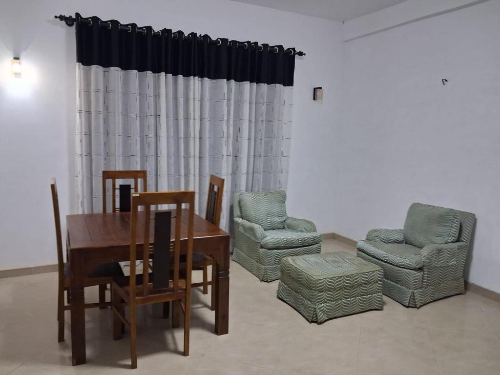 a dining room with a wooden table and two chairs and a table and chairsktop at Slayan-1 properties in Mudungoda