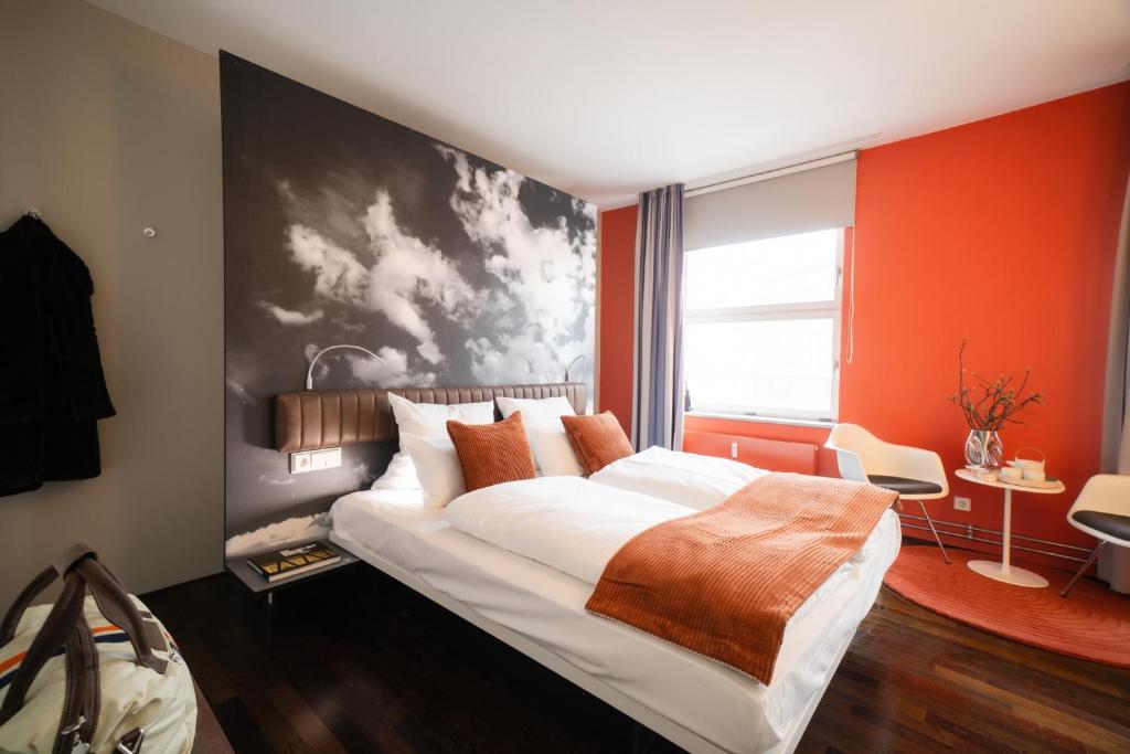 a bedroom with a large bed with orange walls at Motorworld Inn Hotel Böblingen in Böblingen