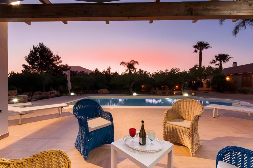 a patio with two chairs and a table with a bottle of wine at Villa Le Sterlizie in Castellammare del Golfo