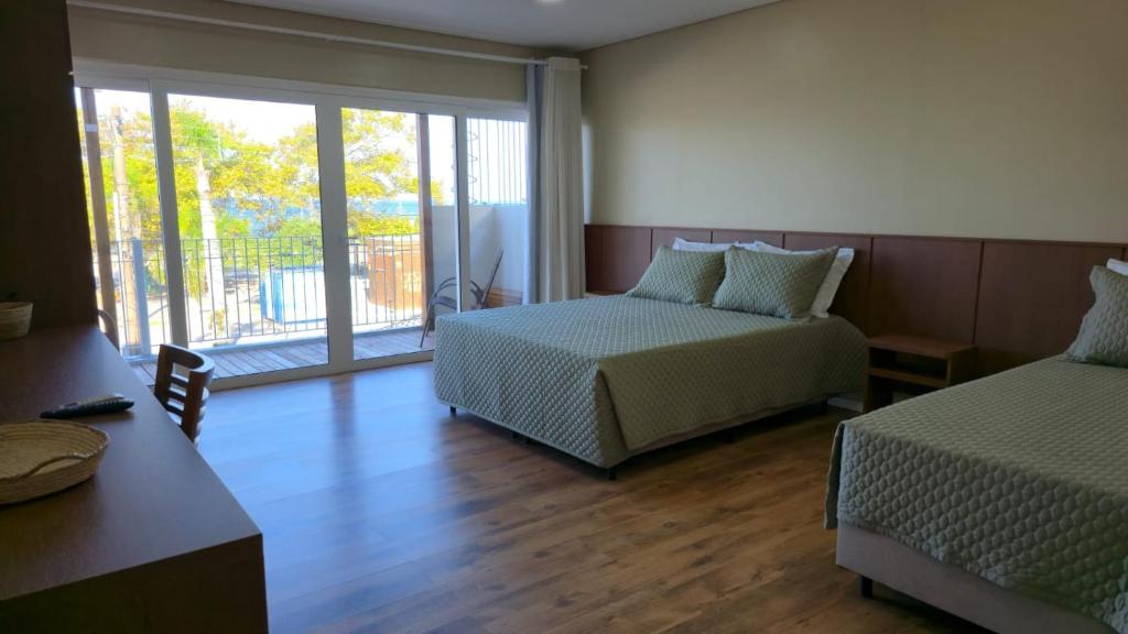 a hotel room with two beds and a window at Pousada Trapiche in Pelotas
