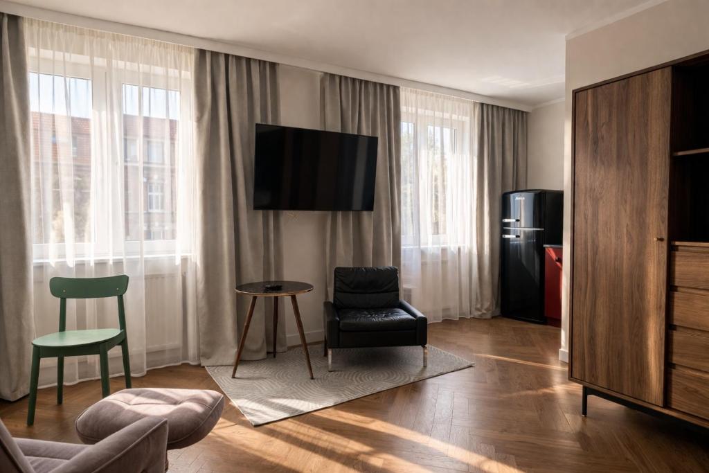 a living room with a television and a chair at Studio Odrodzenia 5 Centrum Lubina in Lubin