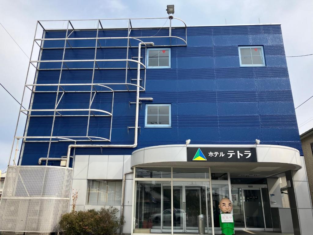 a blue building with a boy standing in front of it at Hotel Tetora HonHachinohe in Hachinohe