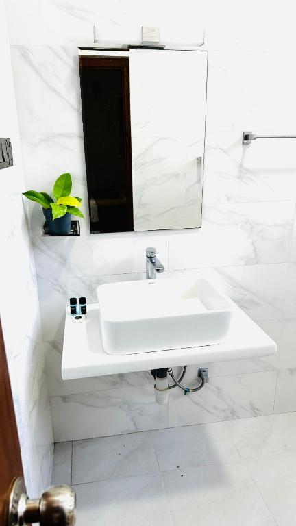 a white bathroom with a sink and a mirror at Infinity Villa in Anuradhapura