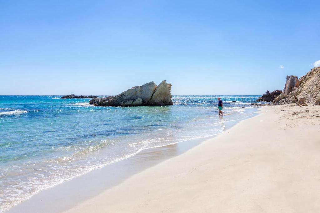a person walking on a beach near the ocean at Es Claper Cala Ratjada in Cala Ratjada