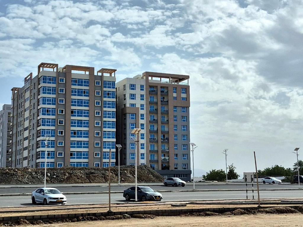 two tall buildings with cars driving on a highway at Beach star residency 2 in Muscat