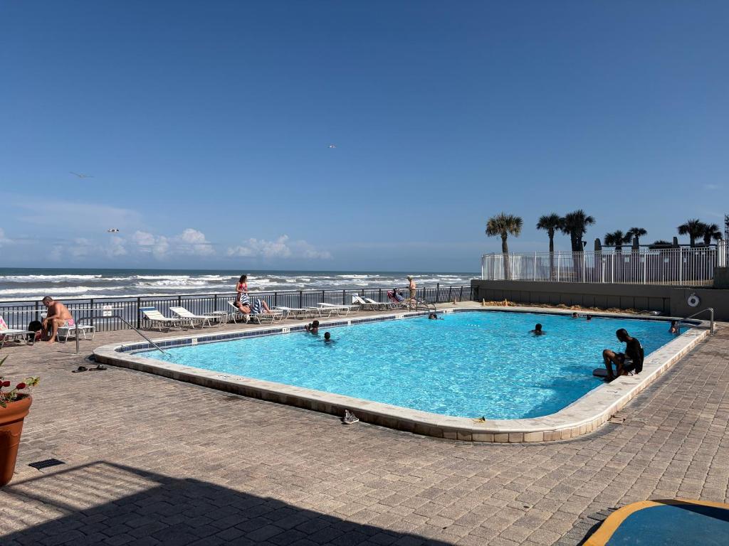 a swimming pool with people in it next to the beach at Single, Double or Quad Oceanview Studios - Direct Beach Access, Oceanfront Pool & Tiki in Daytona Beach Shores