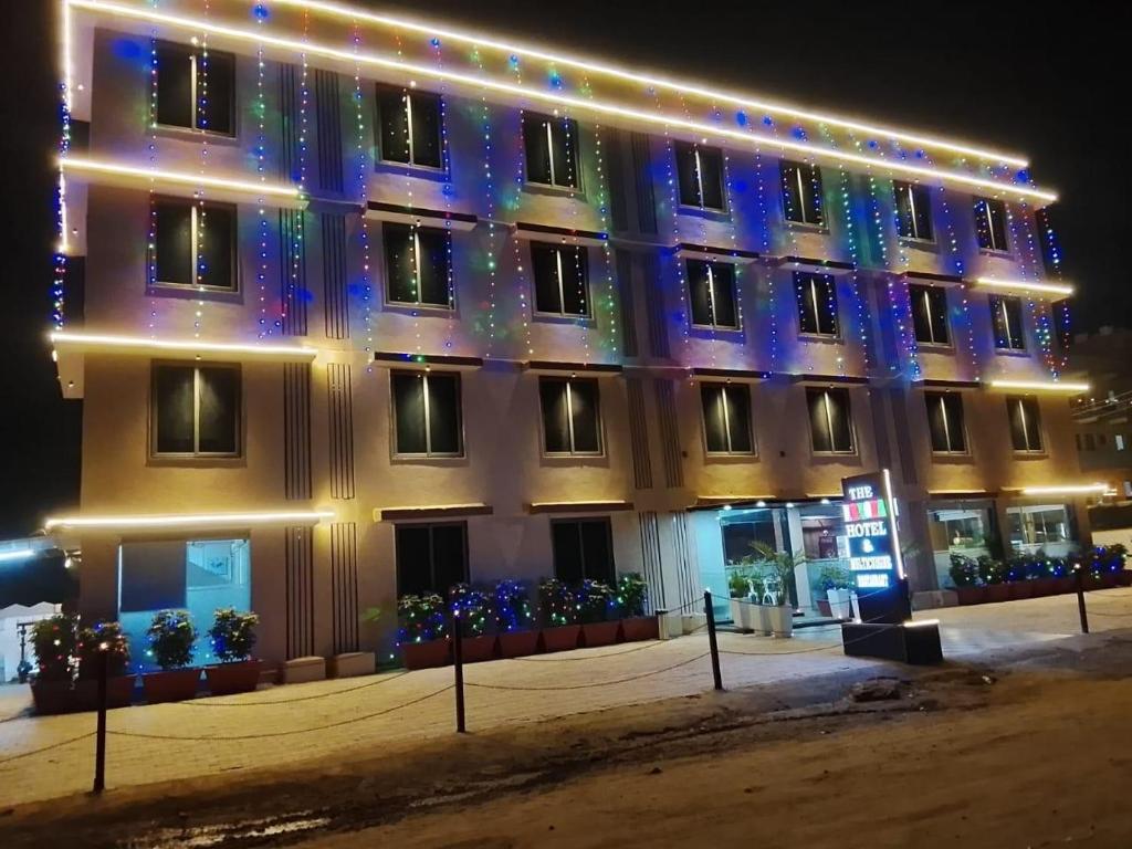 a building with christmas lights on the side of it at Lexora Hotel in Chharodi