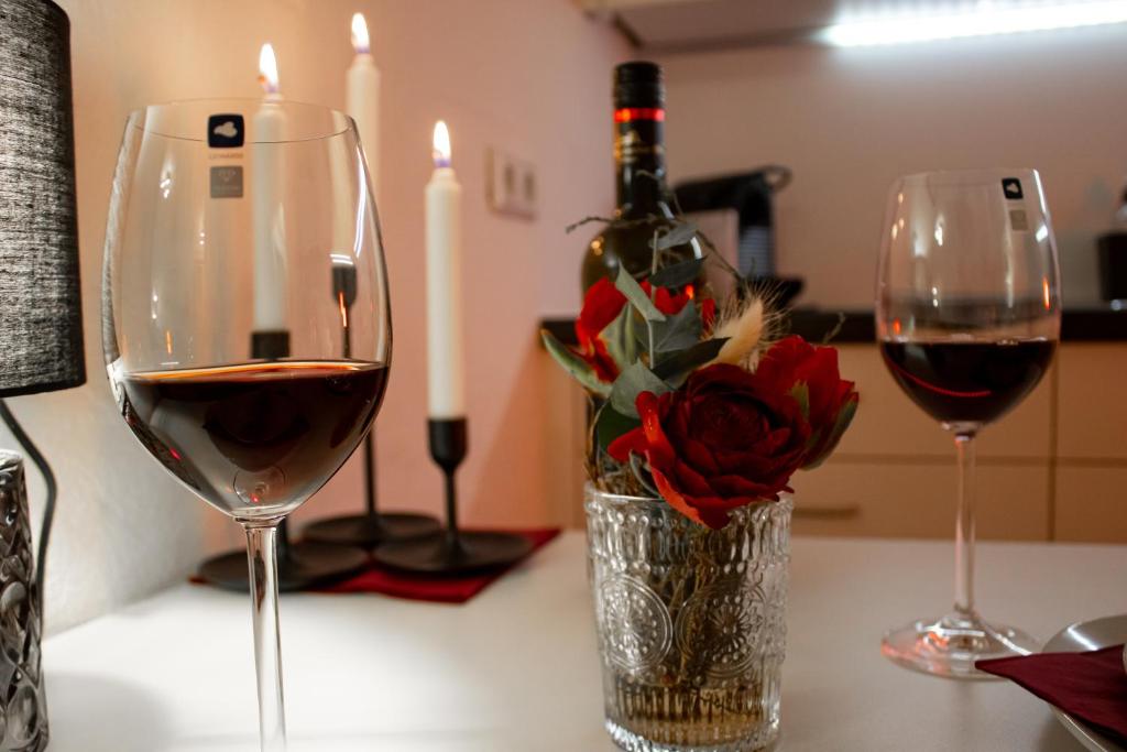 two glasses of wine and a vase of flowers on a counter at Ferienwohnung Bela in Wangen im Allgäu