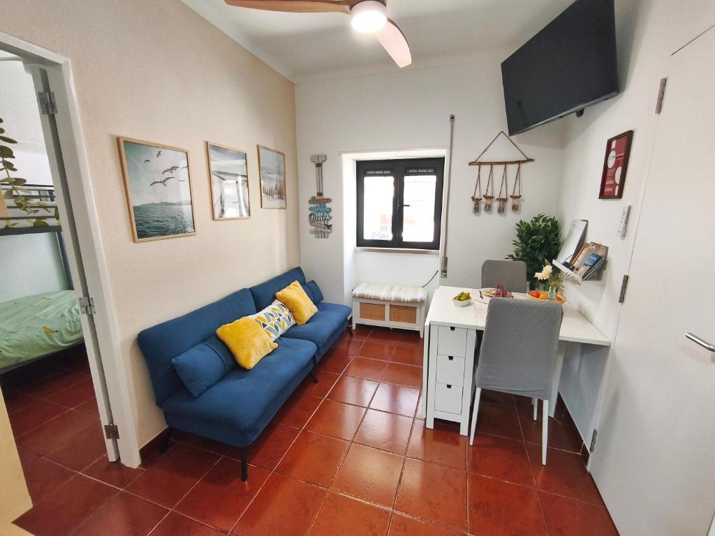 a living room with a blue couch and a desk at Sesimbra Fé House in Sesimbra