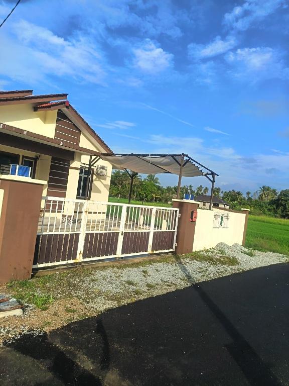 a house with a white fence with a canopy on it at D'sawah Guest House in Kota Bharu