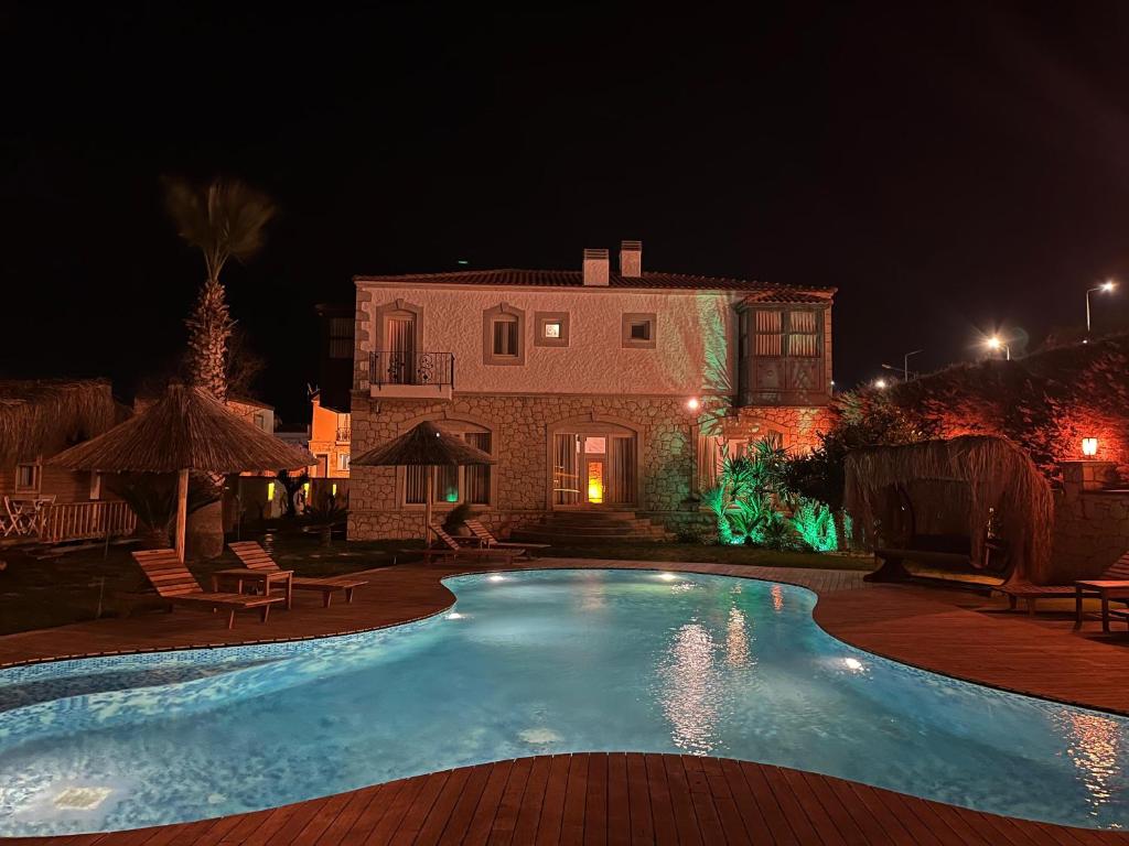 a swimming pool in front of a house at night at Müptela Alaçatı in Çeşme