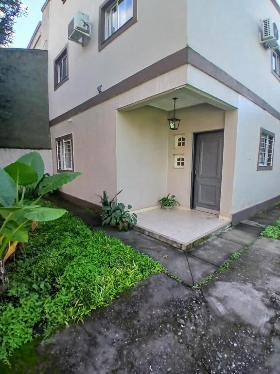 a white house with a door and a yard at Duplex Los Araujos in Yerba Buena