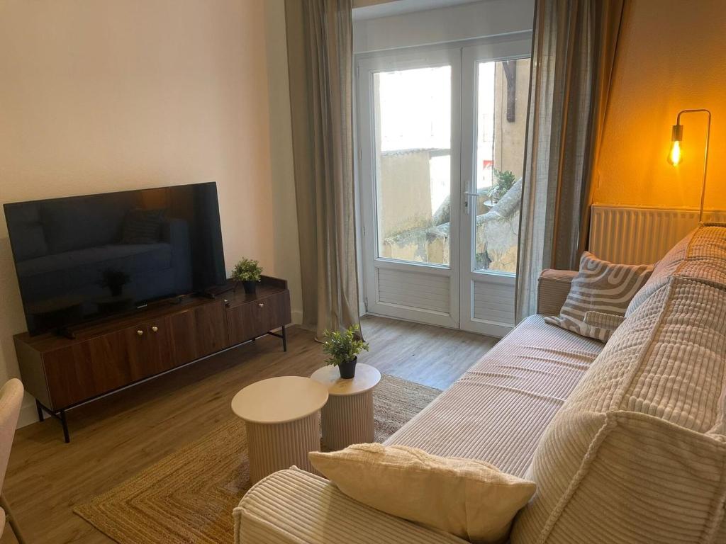 a living room with a couch and a flat screen tv at La Parenthèse de Foch in Le Puy-en-Velay