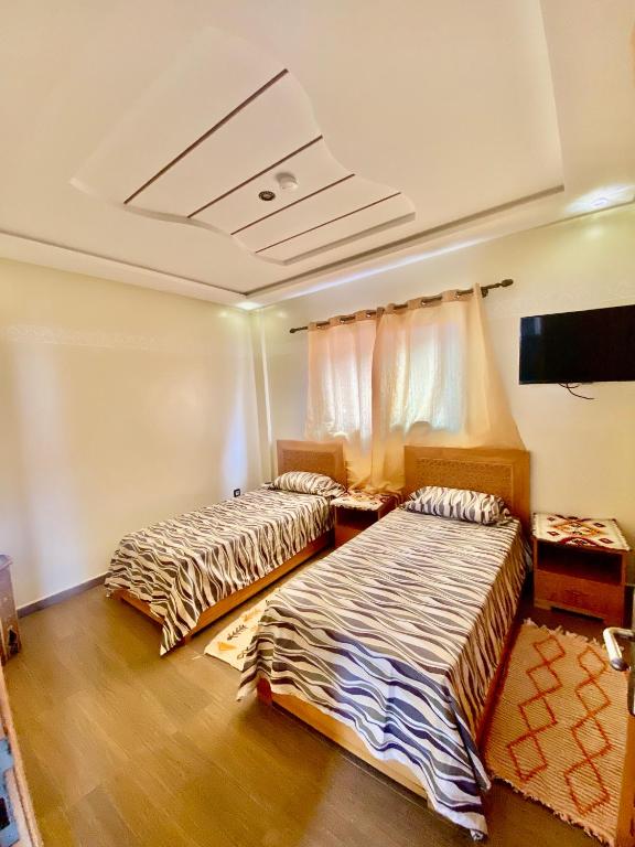 a room with two beds and a tv at Genova surf house in Imsouane