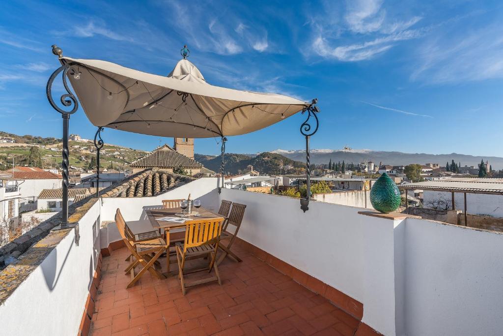 a patio with a table and chairs and a large umbrella at Carmen San Andrés in Granada