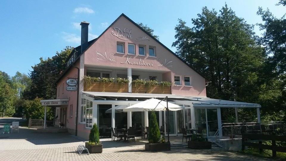 a pink building with an umbrella in front of it at Pension Konditorei Cafe Dora in Münchberg