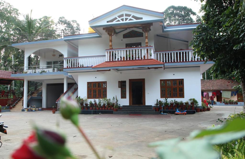 a white house with a balcony on top of it at Kaveri Homestay in Madikeri