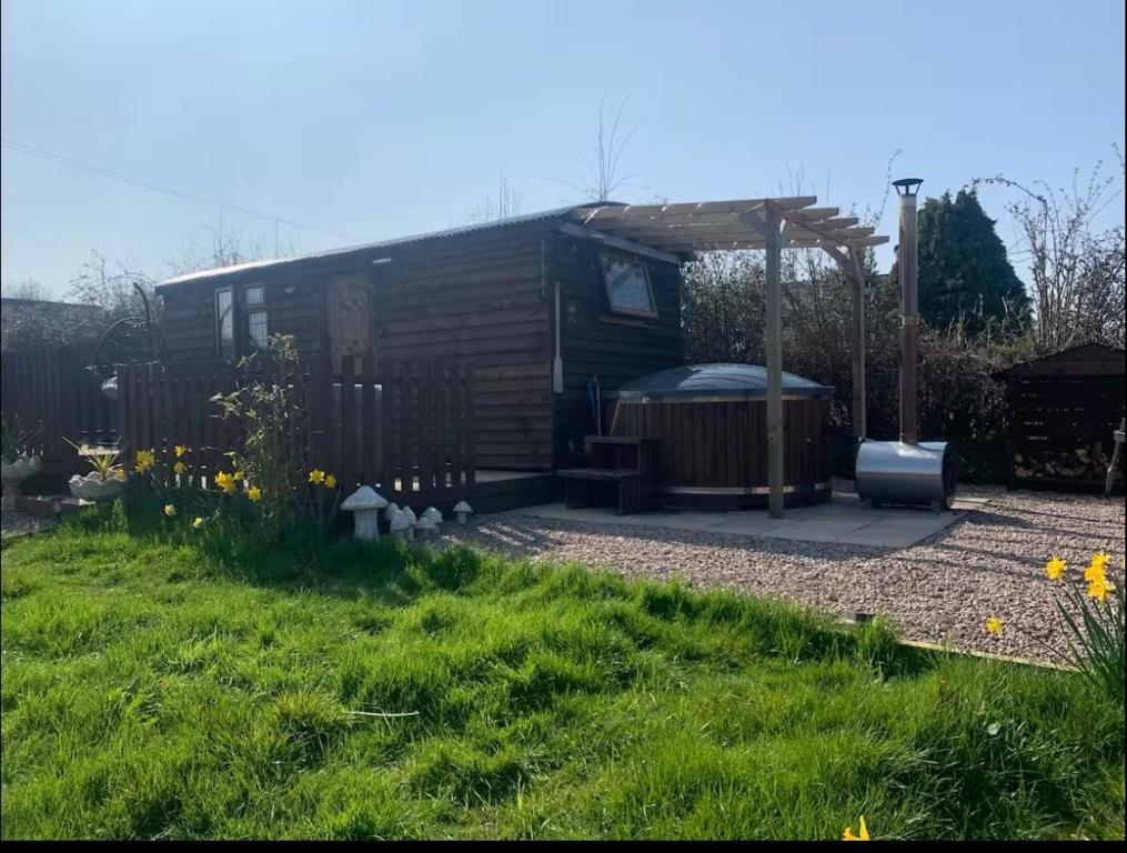 a small cabin with a hot tub in a yard at Four Seasons Mini Zoo Country Retreat with Wood Fuel Hot Tub close to kington Market Town in Hereford