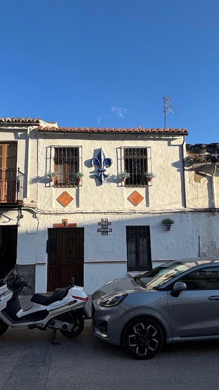 a motorcycle and a car parked in front of a building at La Maison de Magdala in Ronda