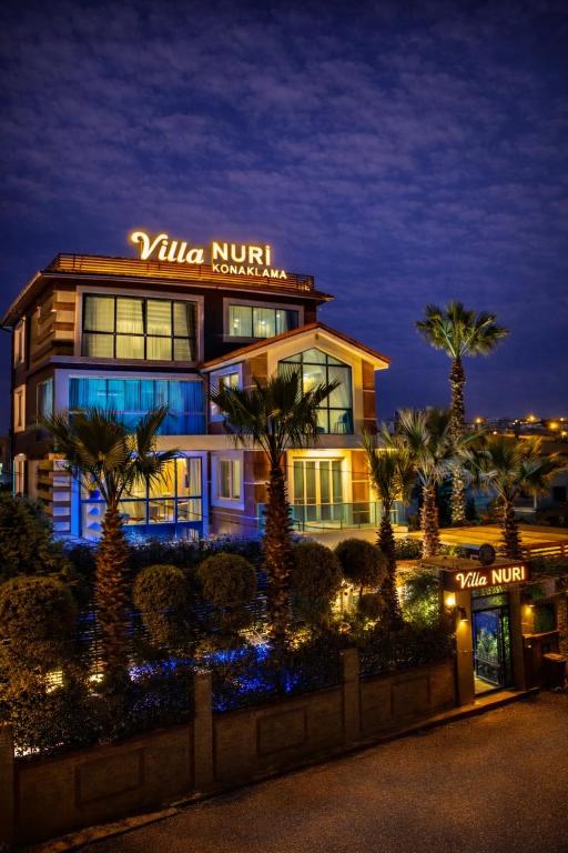 a building with palm trees in front of it at Villa Nuri Konaklama in Çiftlik