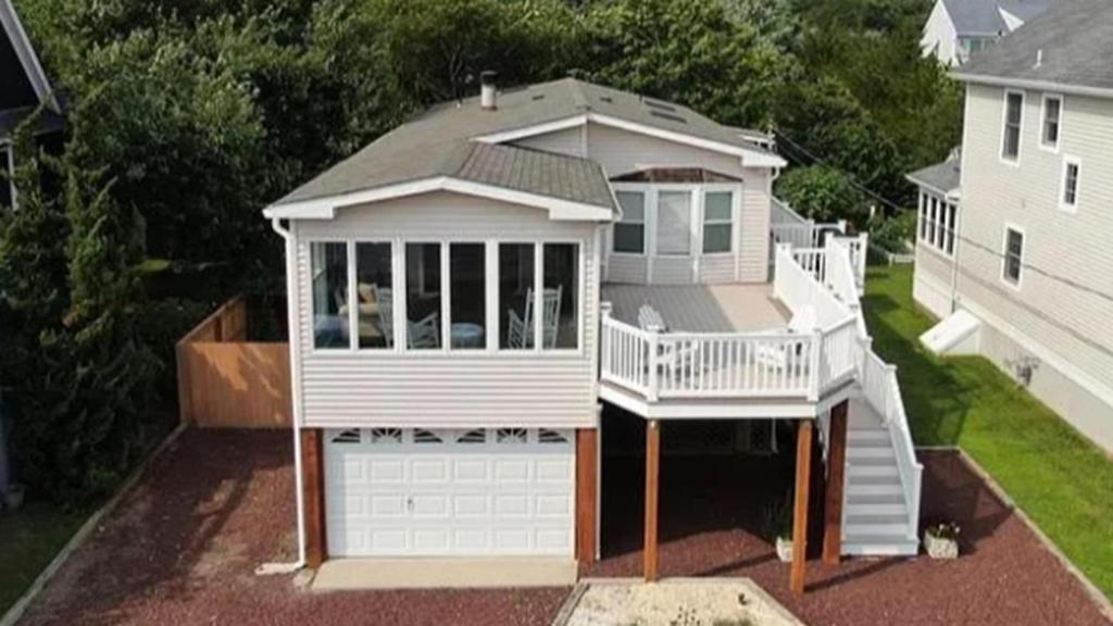 a white house with a porch and a garage at Sunset Shore House Second Floor in West Cape May