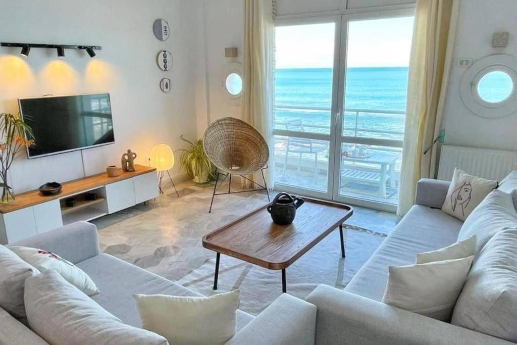 a living room with a view of the ocean at Lappartement Pied dans leau in Douar el Hafey