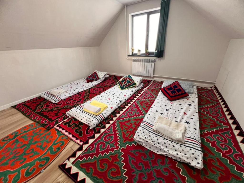 a room with two beds on a rug on the floor at Taldy-Suu Guesthouse in Taldysu