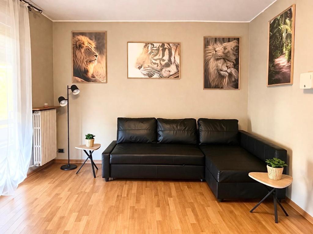 a living room with a black couch and pictures on the wall at Orio Relax&Fly in Grassobbio
