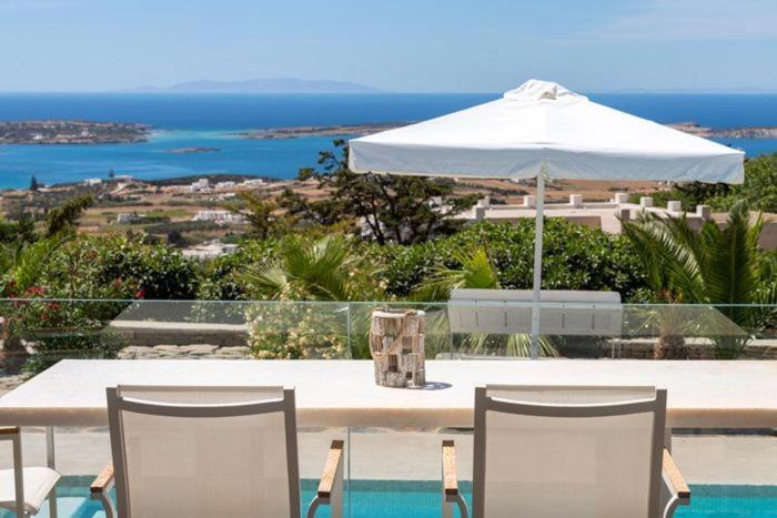 a white table with chairs and an umbrella at Chrysalis Nature Villa 8 in Kampos Paros