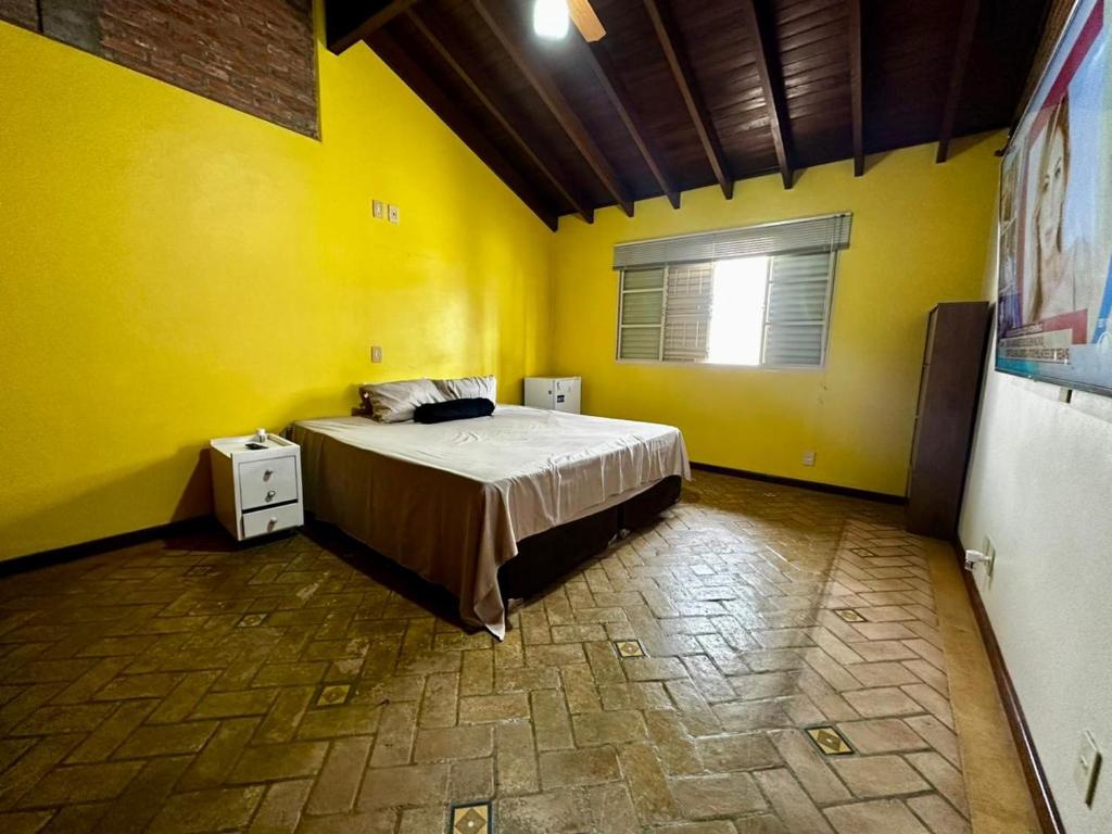a bedroom with a bed in a yellow room at Mega Suíte Na Melhor Localização in Botucatu