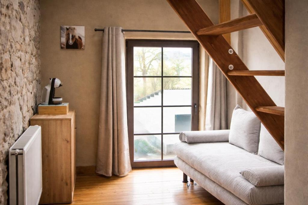 a living room with a couch and a large window at Aux Sabots du Temps in Vielsalm