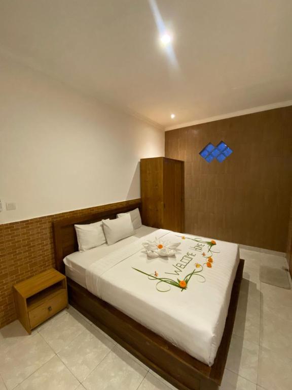 a bedroom with a large white bed with flowers on it at Dava Guest House Gianyar in Gianyar