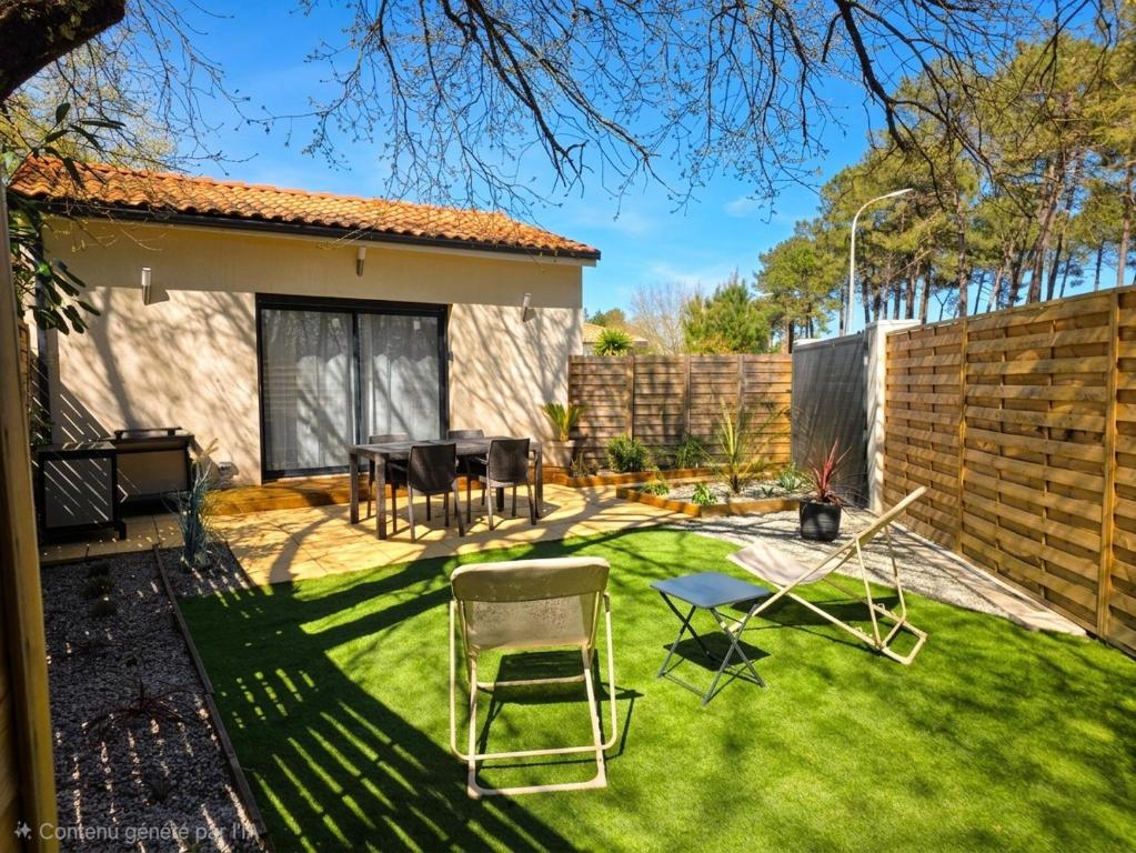 a yard with chairs and a table and a fence at Maisonnette privative Bassin Arcachon in Le Teich