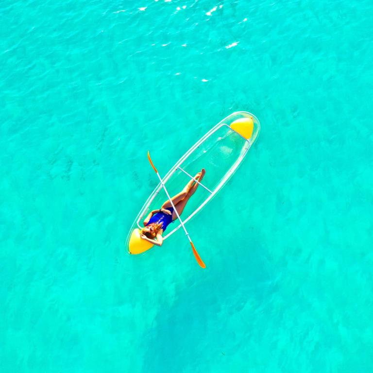 a man riding a paddle board in the water at Adroit Sunset View in Guraidhoo