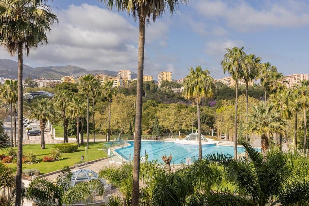 a pool in a park with palm trees at BHost - Bellagio II in Benalmádena