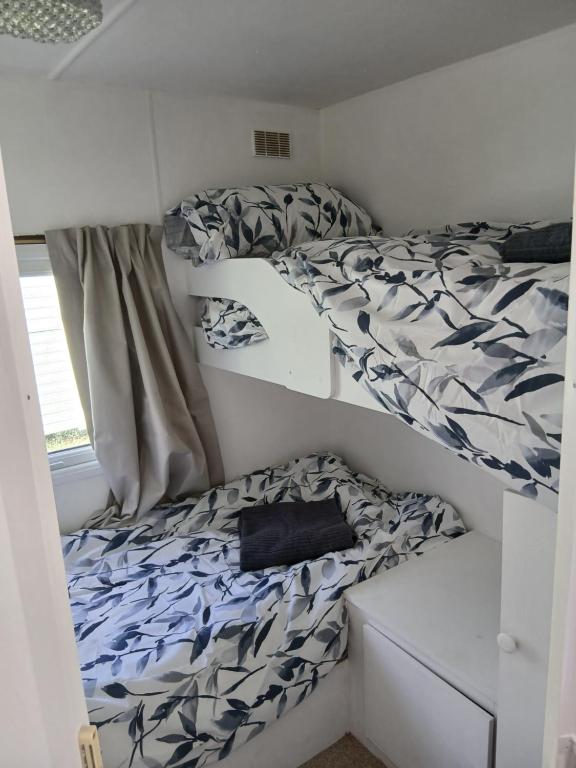 two bunk beds in a small room with a bedskirts at Family friendly static in Pwllheli