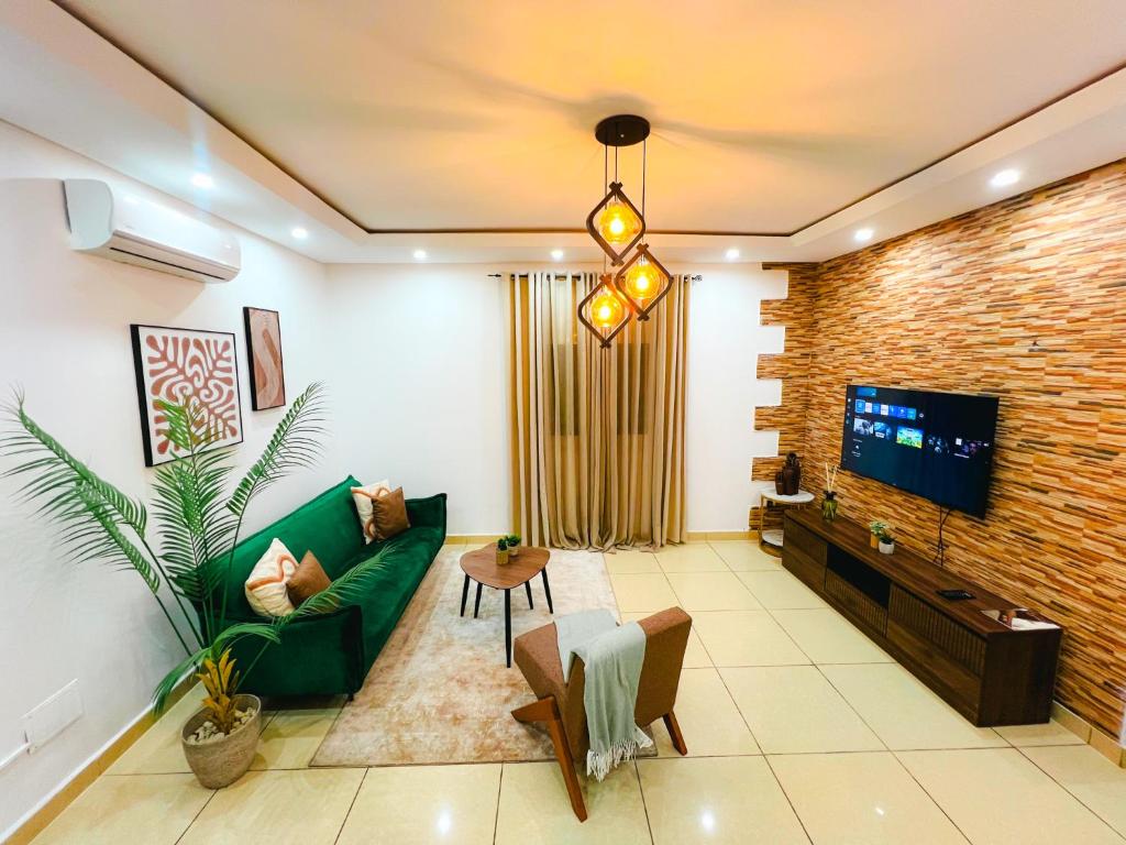 a living room with a green couch and a tv at Suite Kimia - Chic T2, Rue Des Jardins, Cocody, Vallon, Abidjan in Abidjan