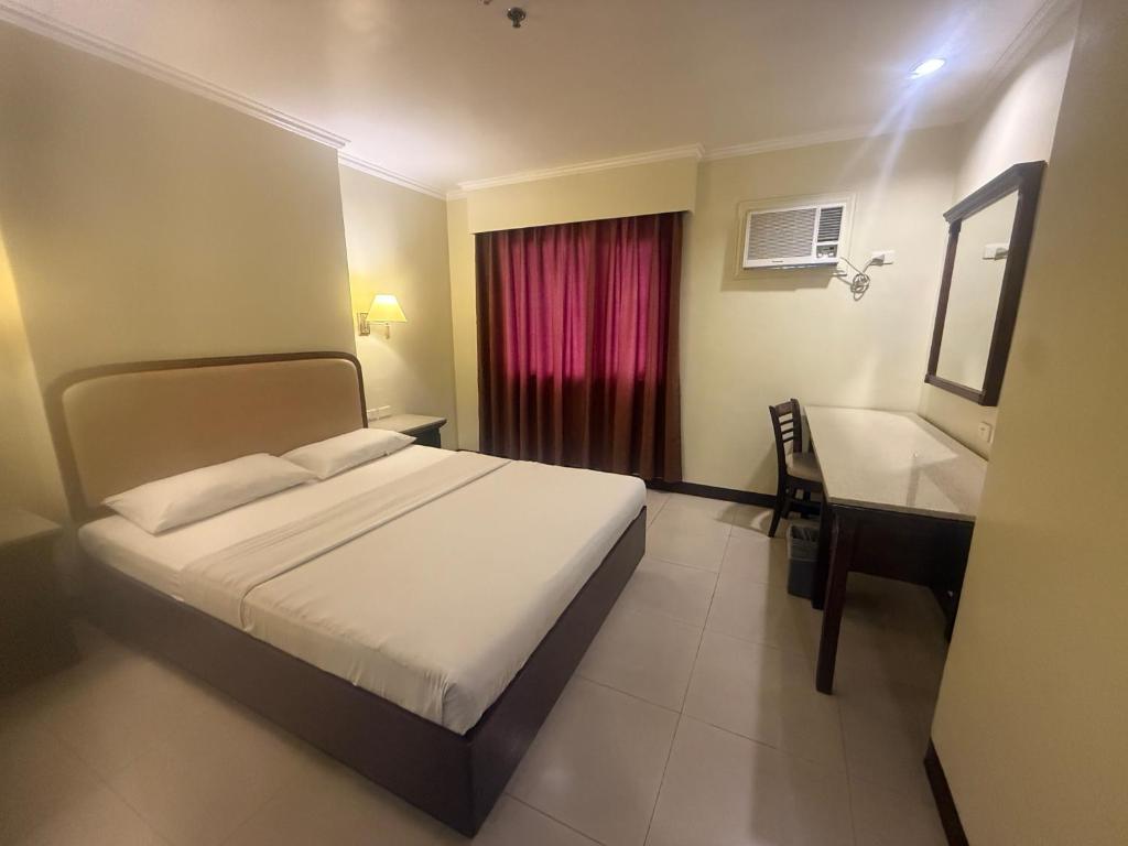 a bedroom with a bed and a desk and a window at W Express Hotel in Cebu City