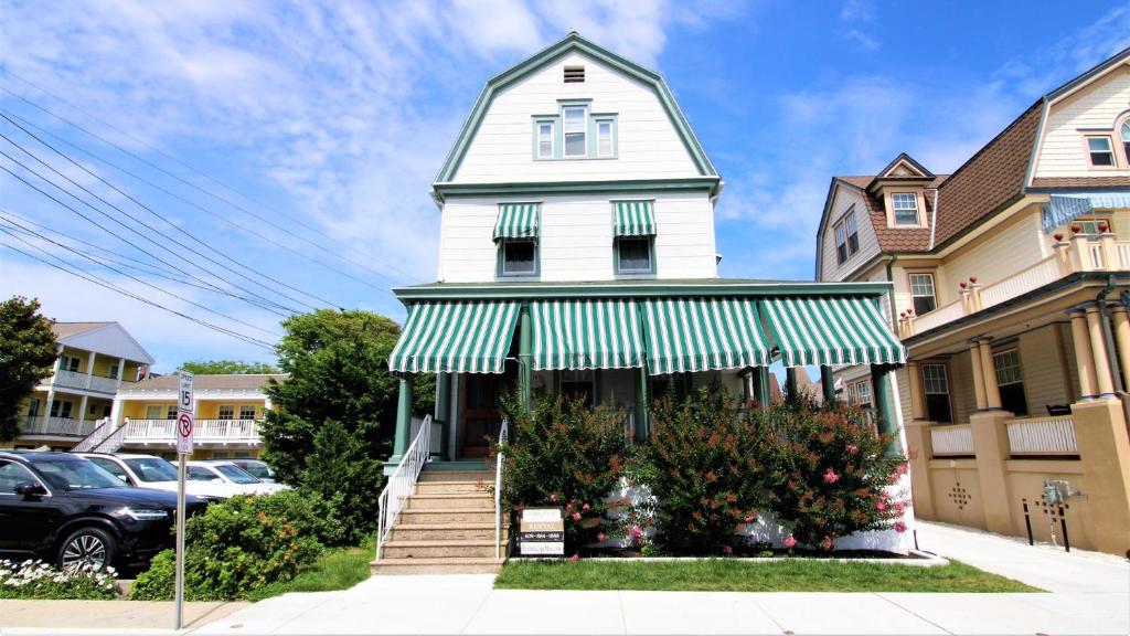 a white house with a green and white awning at The Perry Street Hideaway in Cape May