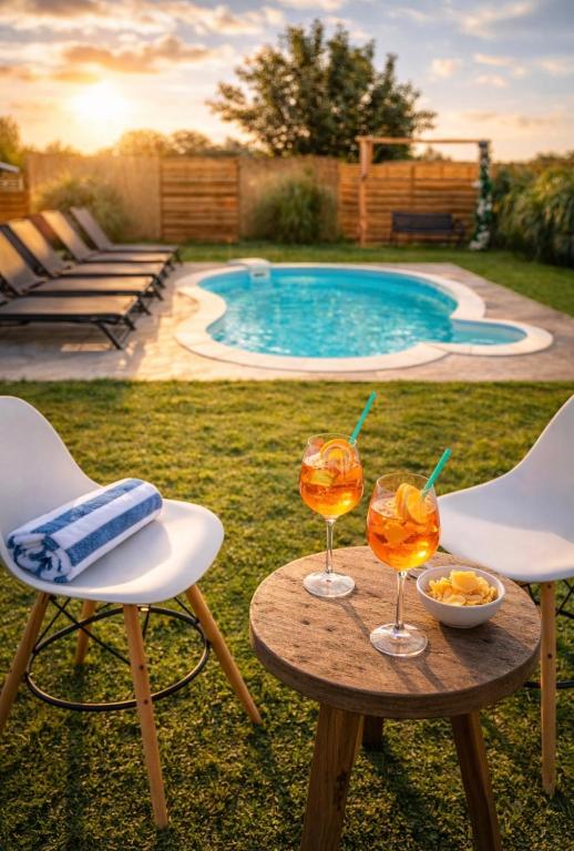 two glasses of wine on a table next to a pool at Kuća za odmor Petra in Erdut