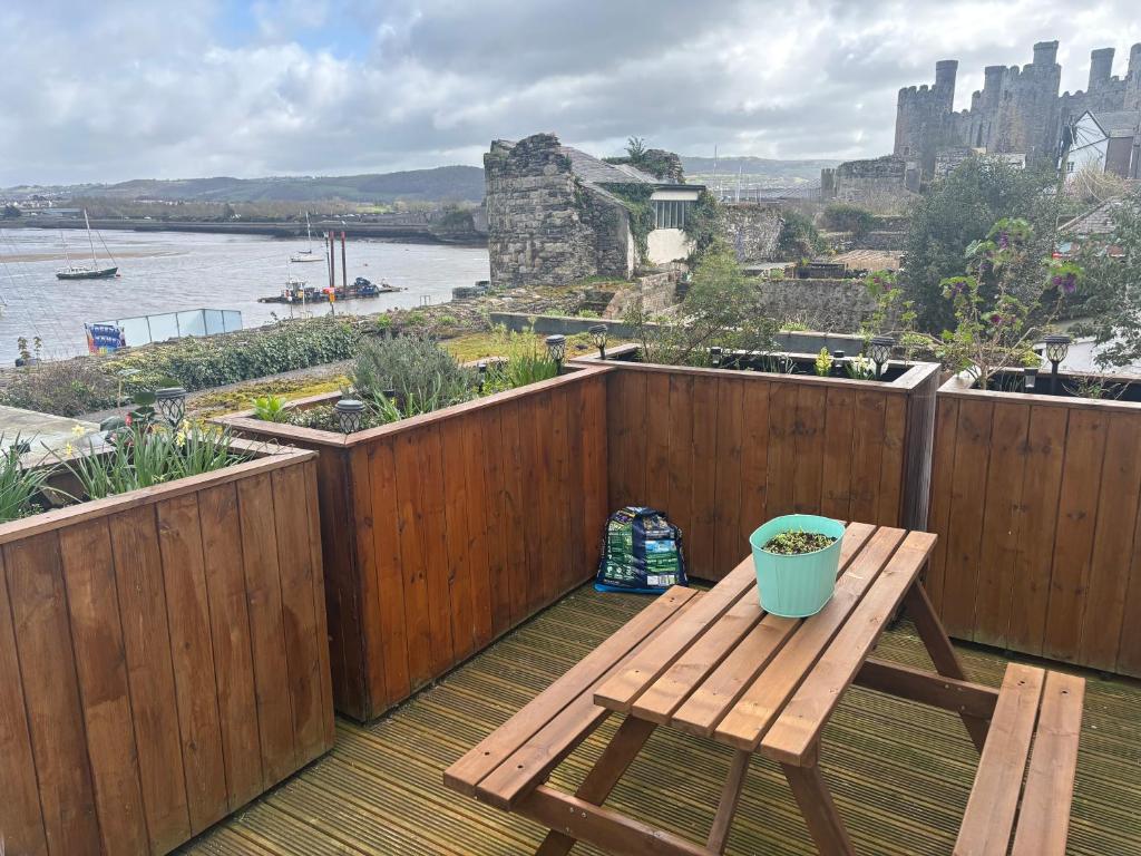 a wooden deck with a wooden table and a bench at Compton House 1, Sea & Castle Views in Conwy