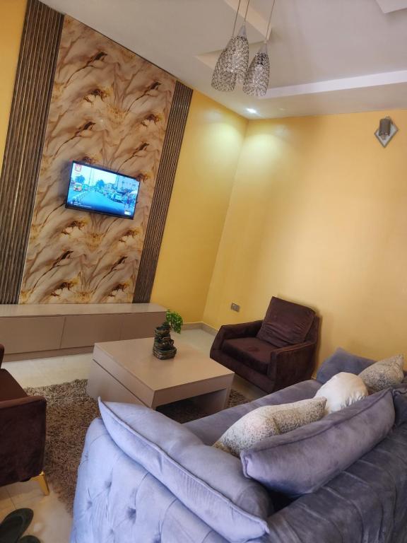 a living room with a couch and a tv on a wall at The Oasis in Oko Erin