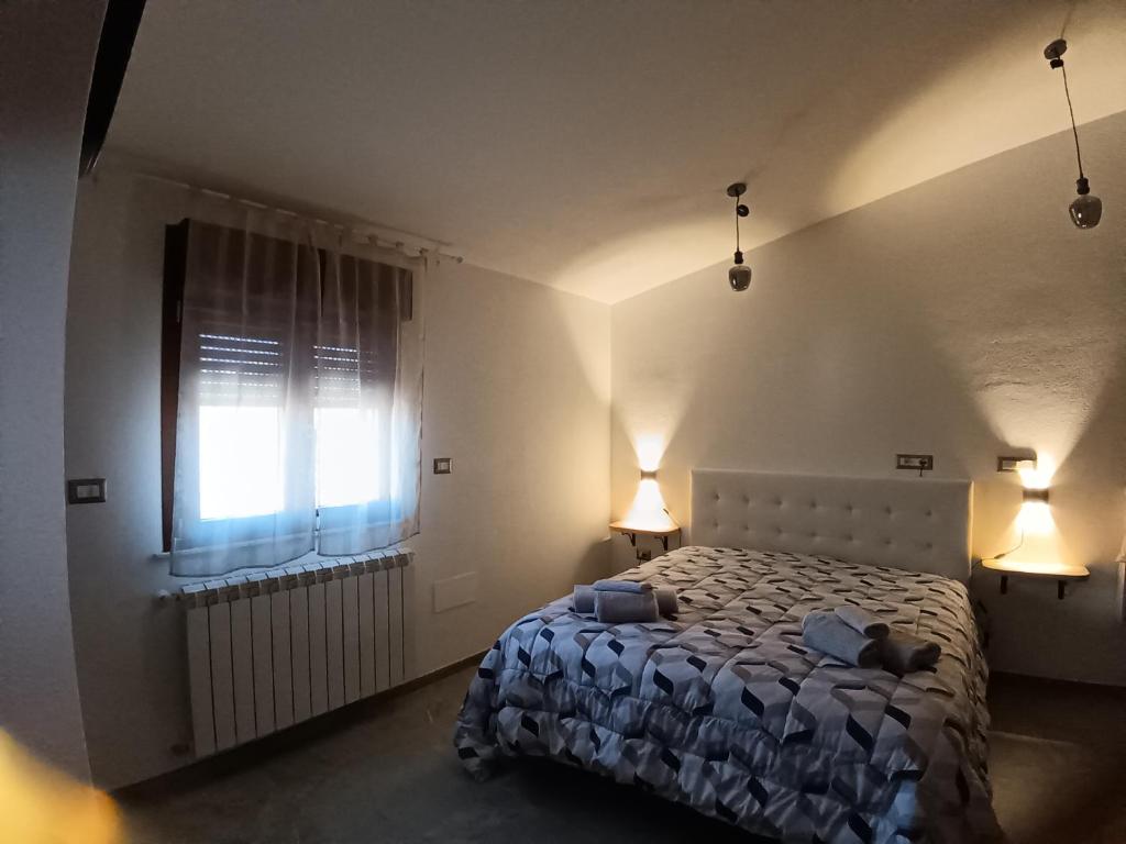 a bedroom with a bed and a window and two lamps at Camera Valeria in Ossi