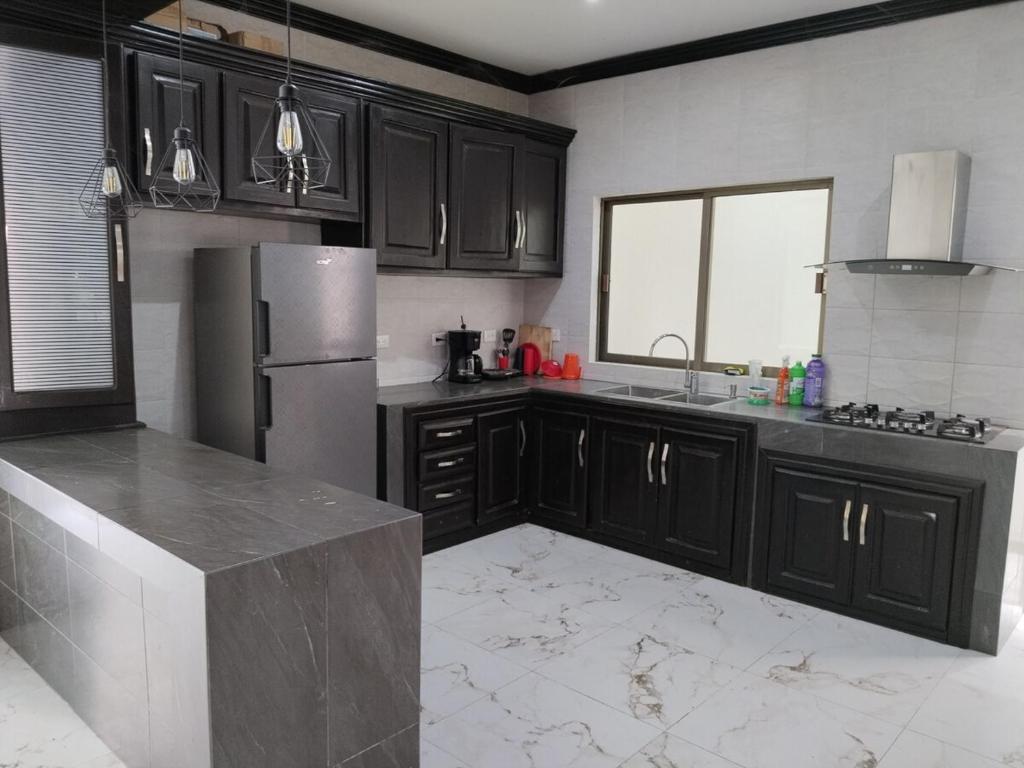 a kitchen with black cabinets and a stainless steel refrigerator at Residencia de Lujo in Tapachula