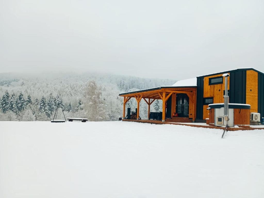 a house on top of a snow covered field at Tiny House Barujec in Brenna