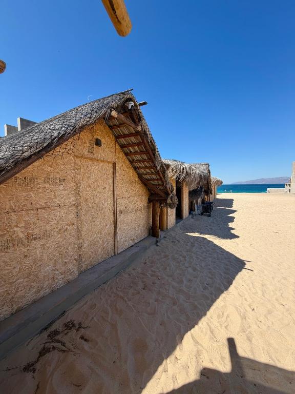 a building on the beach next to the ocean at Salty Sun Cabins Bahía Turquesa in La Ventana