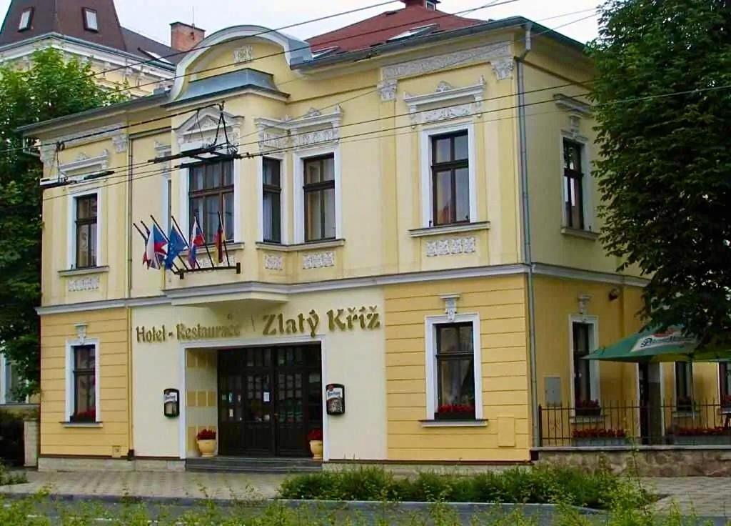 a yellow building with flags in front of it at Hotel Zlatý Kříž in Teplice