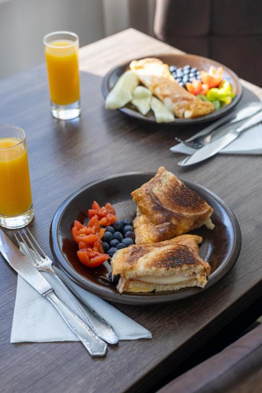 two plates of food on a table with orange juice at Sion Residence in Debrecen