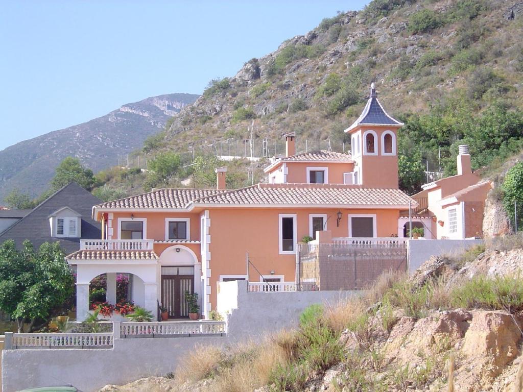 Casa Rural La Torreta في Corbera de Alcira: منزل وردي كبير على تلة مع كنيسة